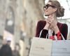 A woman holding a branded shopping bag with a smile.