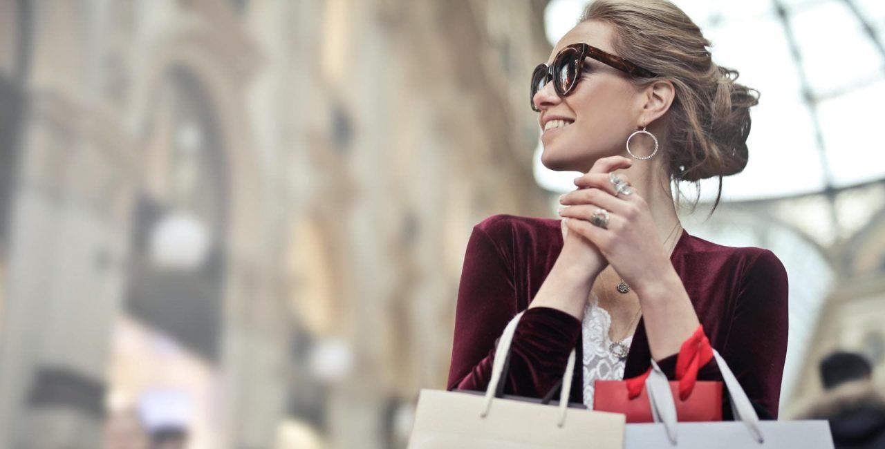 A woman holding a branded shopping bag with a smile.