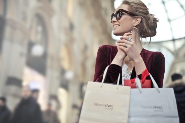 A woman holding a branded shopping bag with a smile.