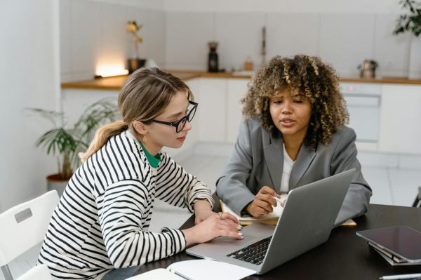 Two women working together on a laptop at a desk.