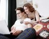 A happy couple browsing products on a laptop, with the woman holding a credit card.