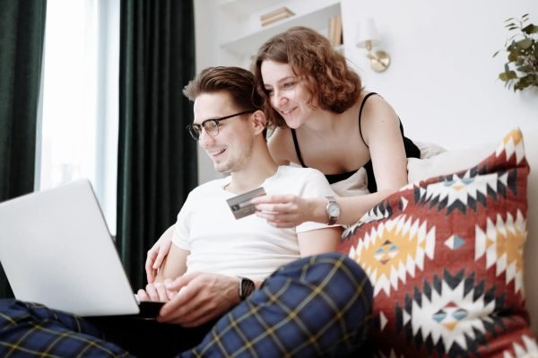 A happy couple browsing products on a laptop, with the woman holding a credit card.