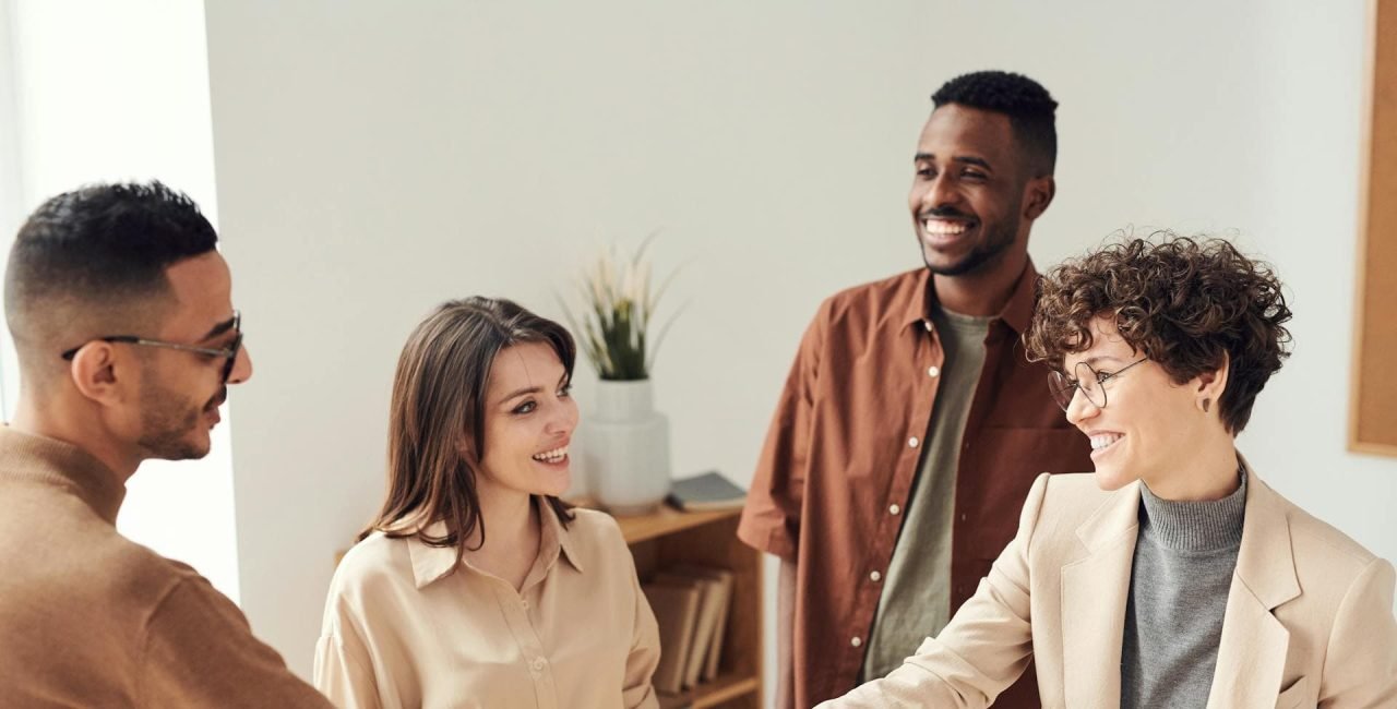 Successful freelance partnership. Happy handshake between freelancer and client, with two other smiling professionals in the background.