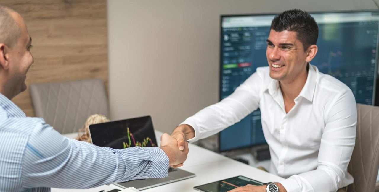 A developer and client shaking hands with happy expressions, symbolizing a successful hiring process.