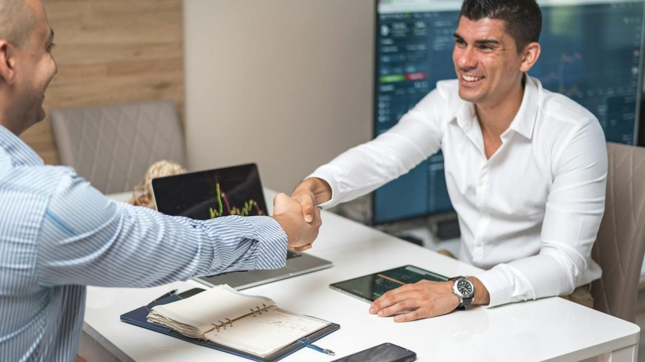 A developer and client shaking hands with happy expressions, symbolizing a successful hiring process.