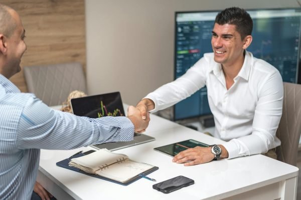 A developer and client shaking hands with happy expressions, symbolizing a successful hiring process.