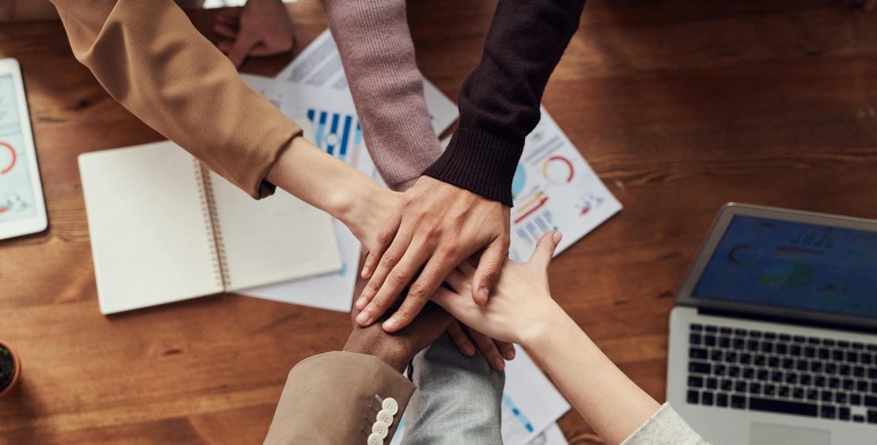 Diverse team collaboration. Six hands coming together in a circle, symbolizing teamwork and unity.