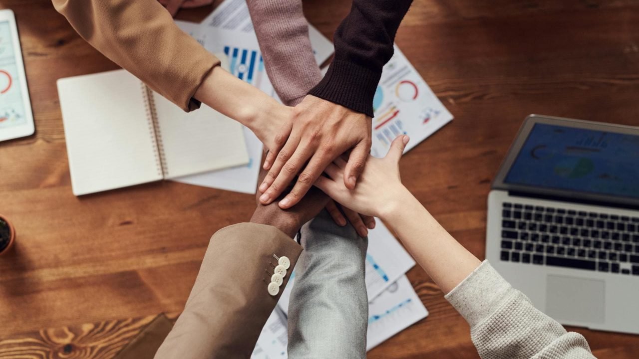 Diverse team collaboration. Six hands coming together in a circle, symbolizing teamwork and unity.