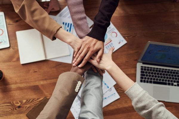 Diverse team collaboration. Six hands coming together in a circle, symbolizing teamwork and unity.